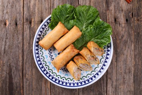 Free Crispy spring rolls with lettuce served on a decorative plate over rustic wood. Stock Photo