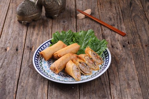 Free A plate of crispy spring rolls served with fresh lettuce on a wooden table. Stock Photo