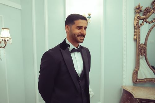 Free Man in a tuxedo smiling indoors in a luxurious, ornate setting in Baghdad. Stock Photo