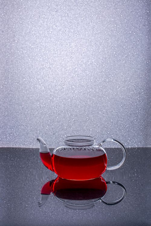 Free Elegant glass teapot filled with red tea, beautifully reflected on a shiny surface. Stock Photo
