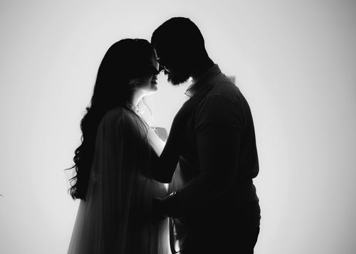 Free Silhouette of a couple embracing with a backlit glow, symbolizing love and intimacy. Stock Photo