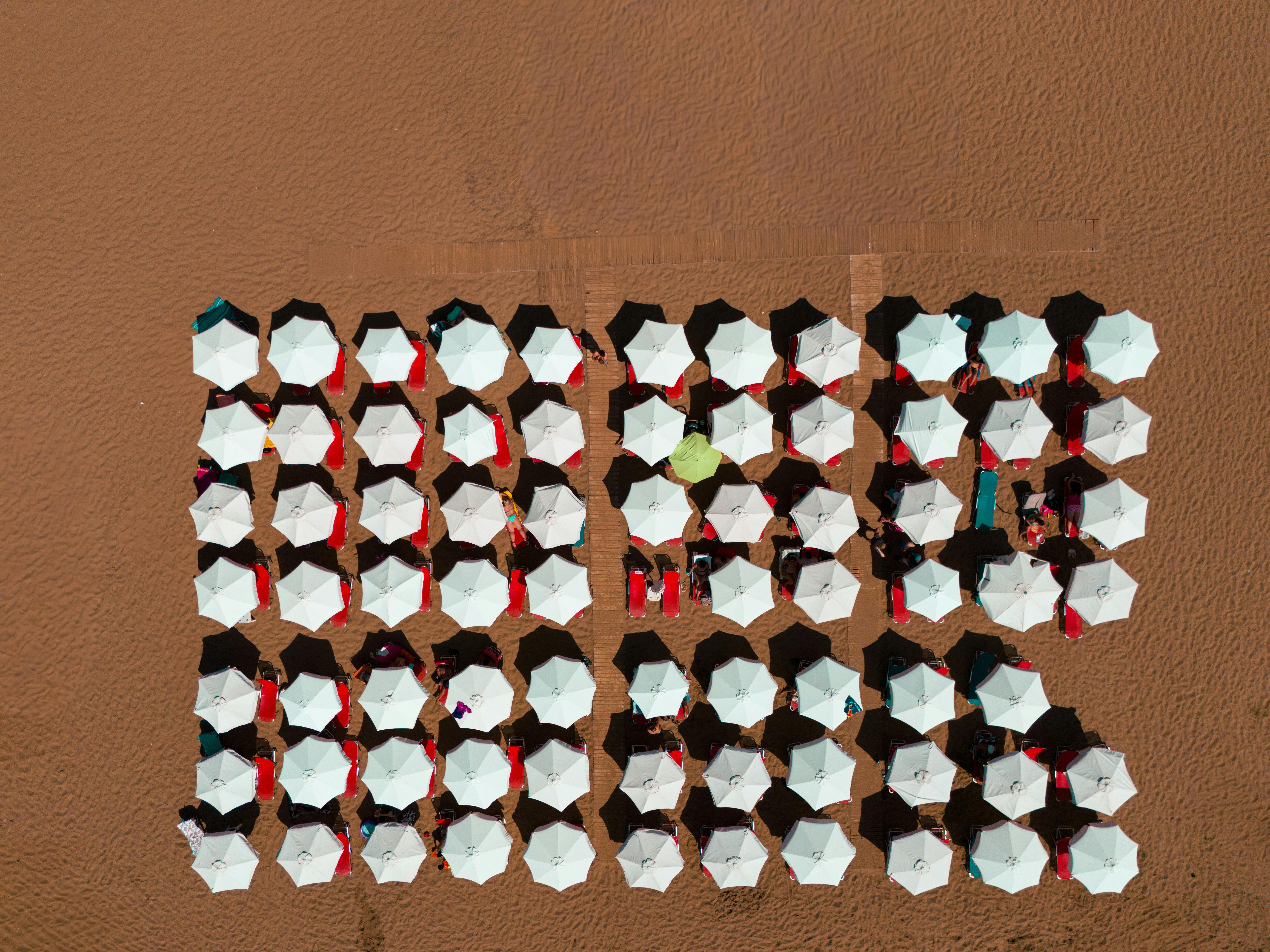 Gratuit Vue aérienne de parasols blancs disposés sur une plage de sable en Grèce, offrant une vue symétrique. Photos