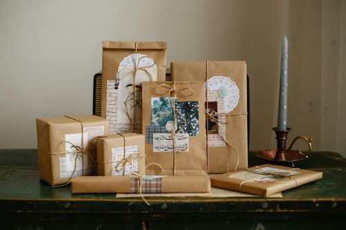 Free Beautifully wrapped gifts in brown paper with twine and vintage decorations, beside a candle holder. Stock Photo