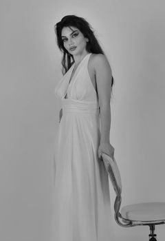 Black and white portrait of a woman in an elegant white dress indoors, exuding classic style.