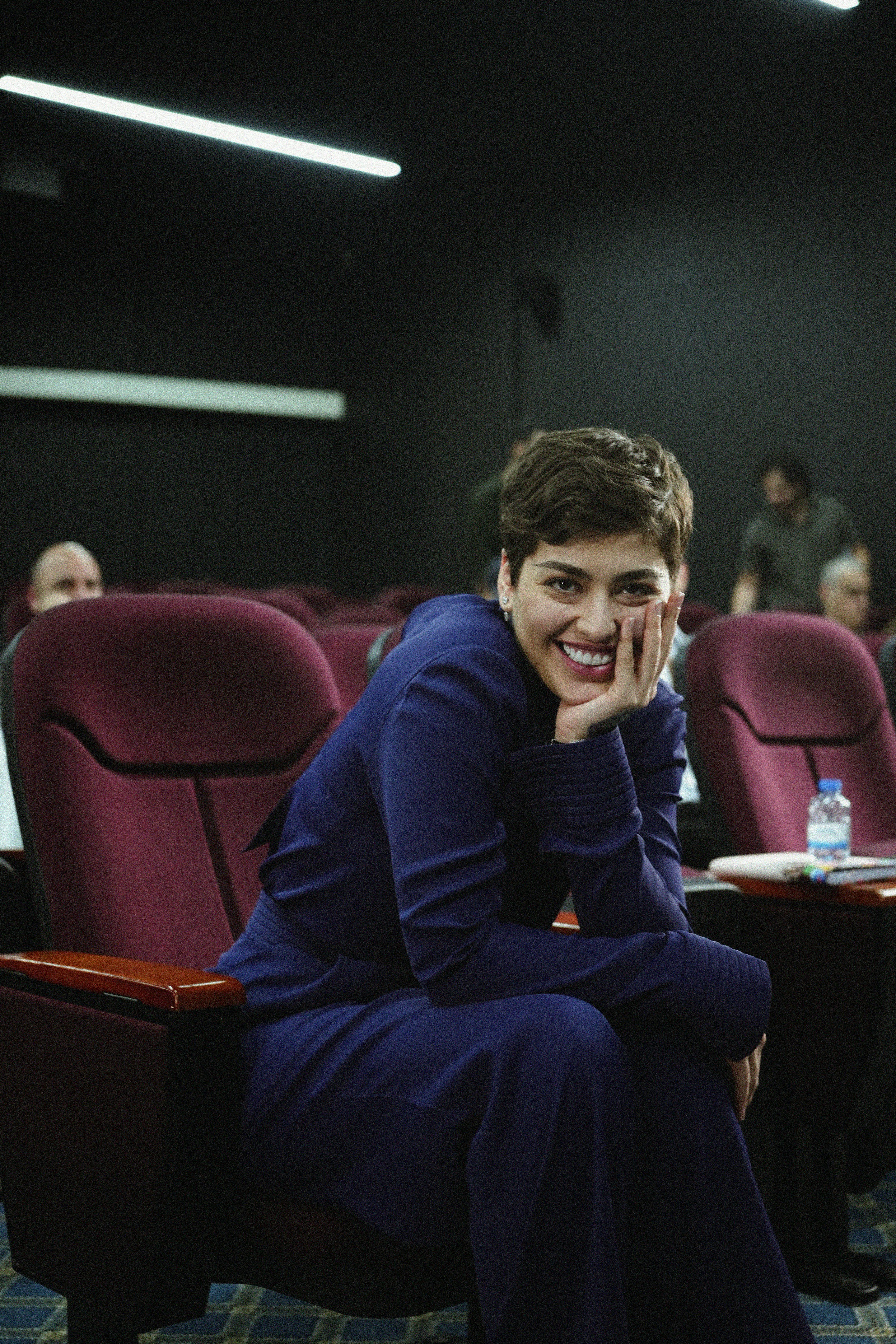 Confident woman smiling in theater seating during seminar.