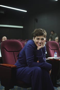 Confident woman smiling in theater seating during seminar.