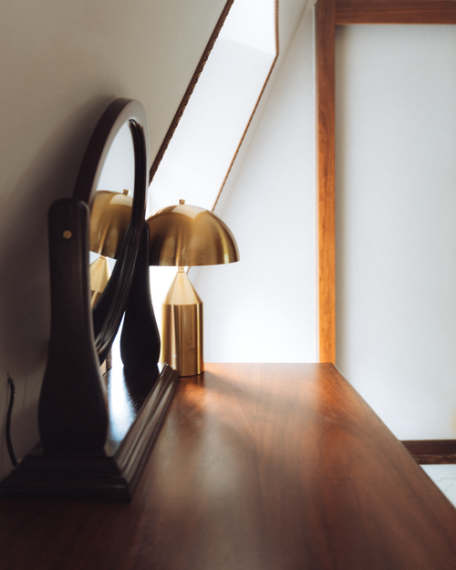 Free Elegant minimalist interior with a wooden desk, gold lamp, and mirror reflecting light. Stock Photo