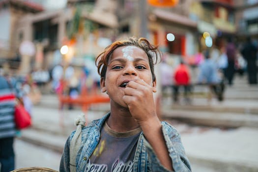 A joyful child with painted forehead in the lively streets of Varanasi, India, capturing cultural vibrancy.