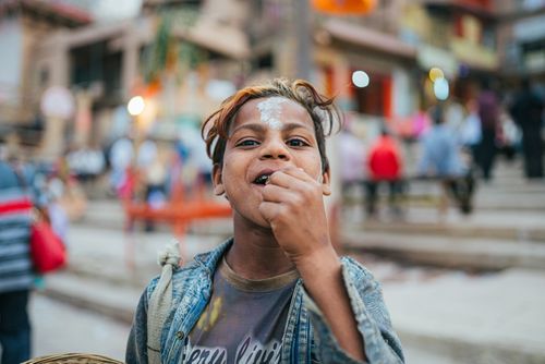 Free A joyful child with painted forehead in the lively streets of Varanasi, India, capturing cultural vibrancy. Stock Photo