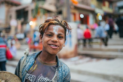 A young boy with painted forehead smiles in the lively streets of Varanasi, India.