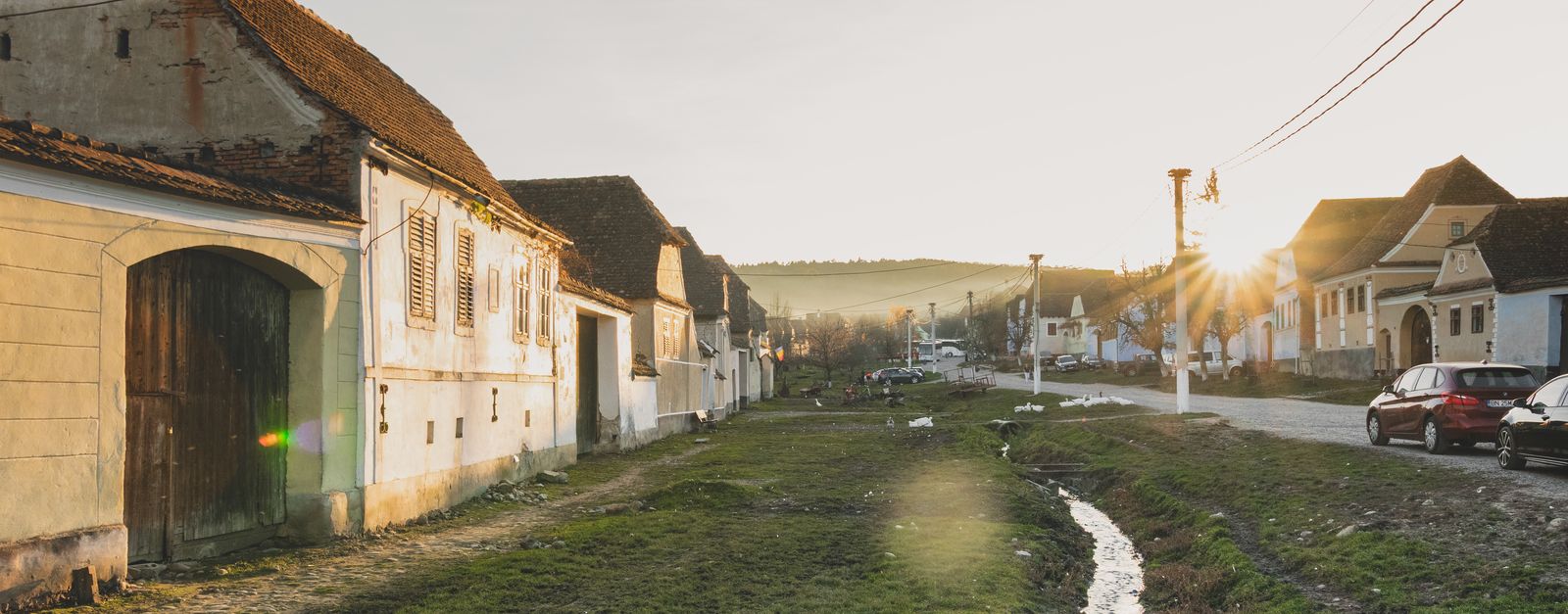 A serene village in Romania during sunset, featuring rustic houses and a peaceful landscape.