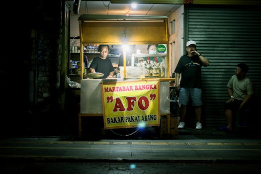 A vibrant street food vendor stall by night, serving Martabak Bangka 'AFO' in a bustling market scene.