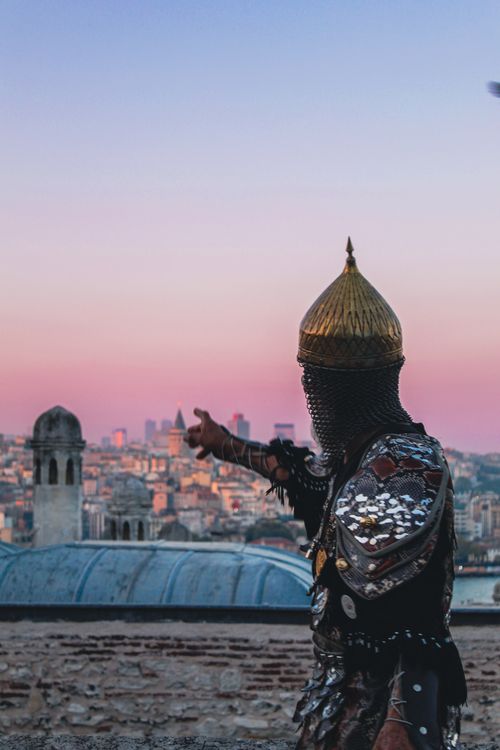 Free A medieval knight in armor overlooks the cityscape of Istanbul at sunset, capturing historical essence. Stock Photo