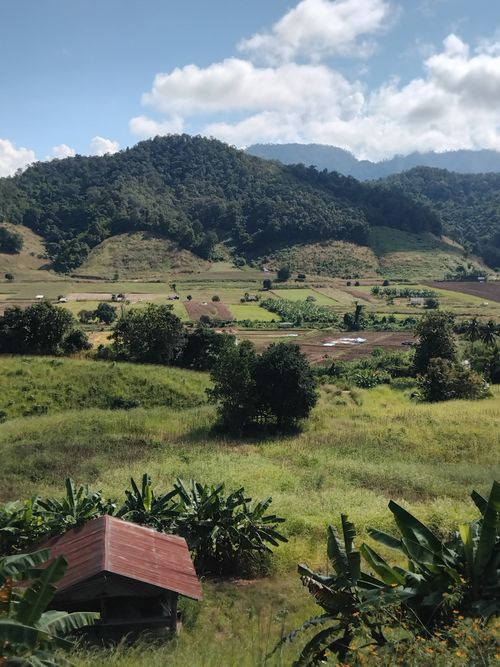 Free Breathtaking view of lush green valley surrounded by mountainous landscape under blue skies. Stock Photo