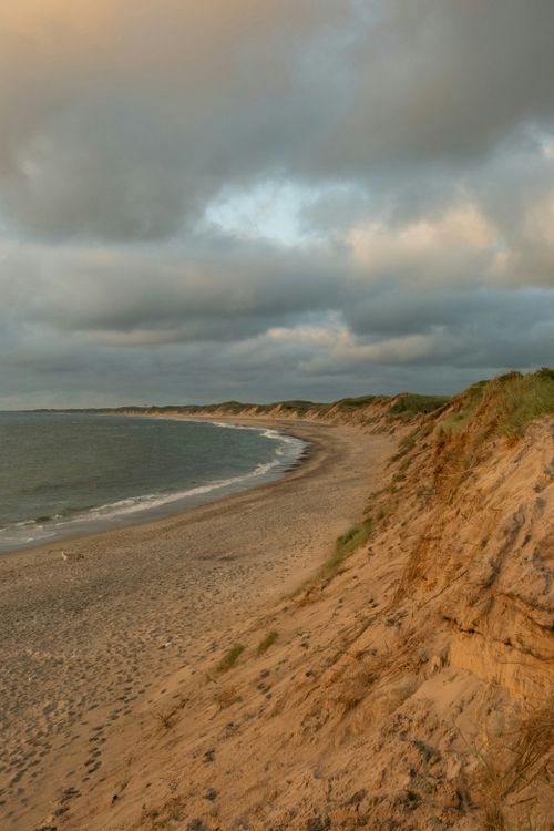 Free Dramatic coastal cliffs and serene beach in Thisted, Denmark at sunset. Stock Photo
