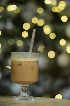 Iced coffee in a glass with a bokeh light background, perfect for holiday themes.