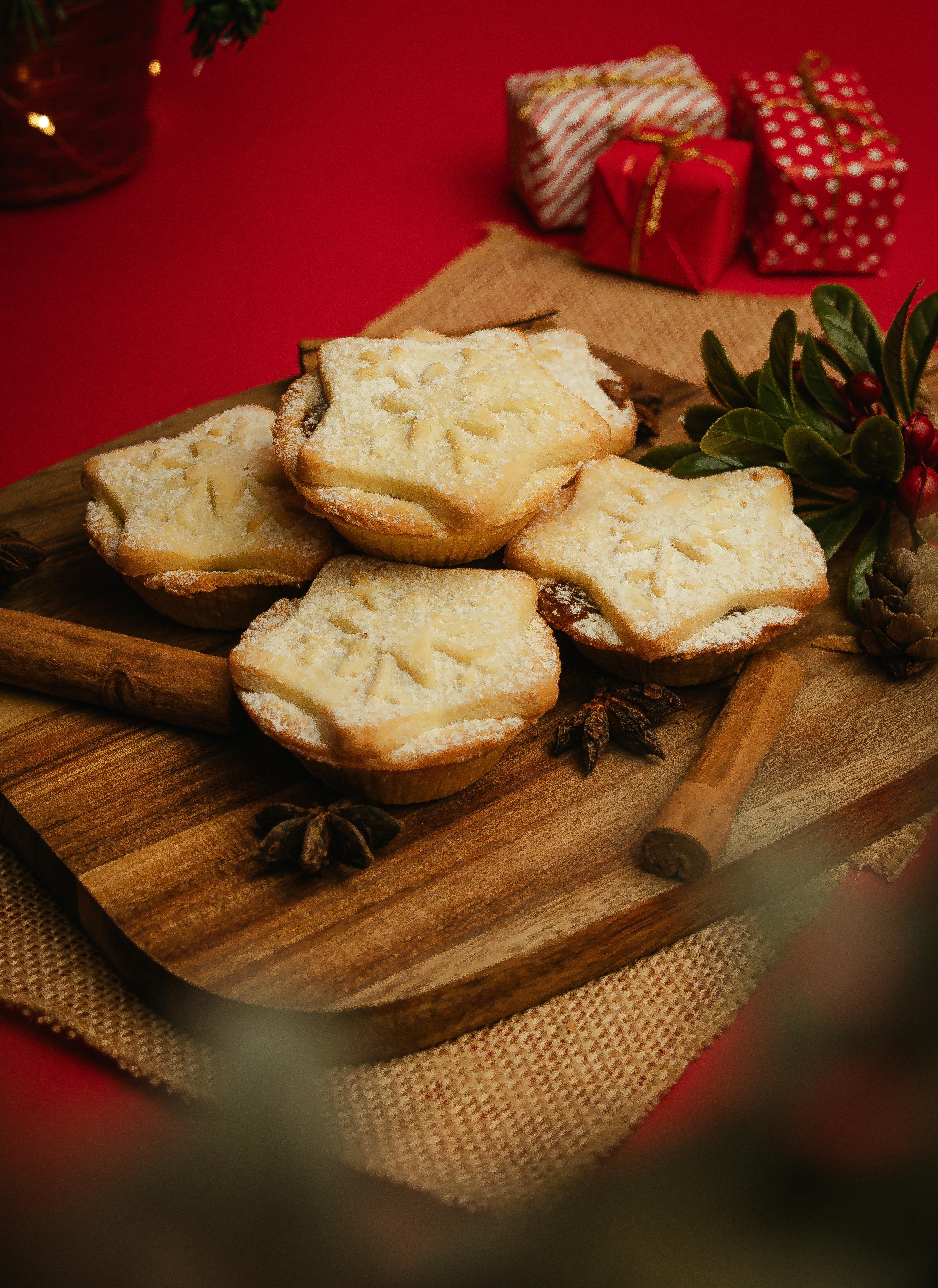 Delicious mince pies with holiday spices on a wooden board, perfect for festive celebrations.
