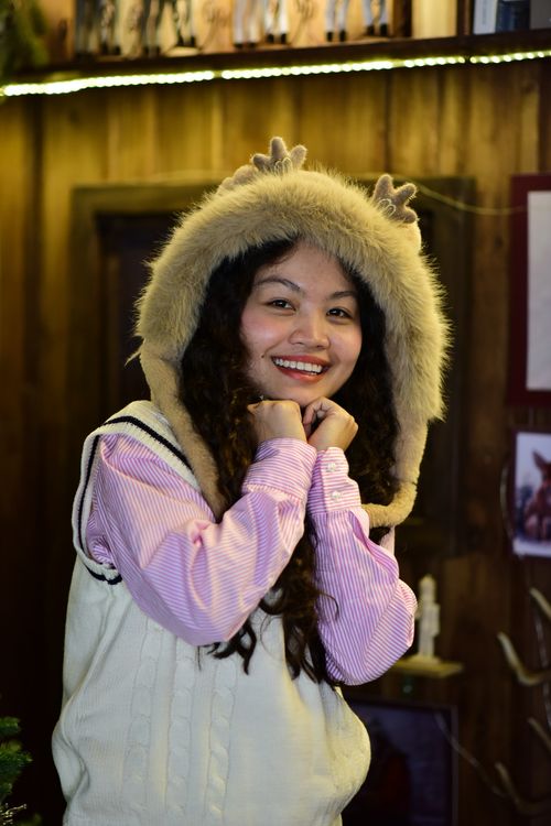 Free Smiling woman in fur hood posing indoors with reindeer antlers hat. Stock Photo