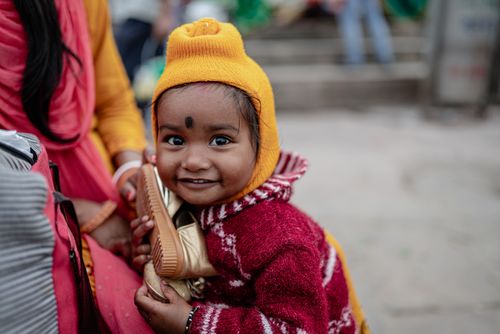 Free A cheerful child in colorful winter attire, embracing a shoe, captured in Varanasi, India. Stock Photo