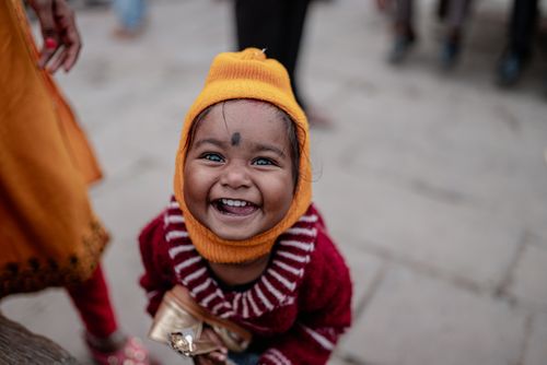 Free Adorable child beaming with joy in colorful winter clothing in Varanasi, capturing a moment of pure happiness. Stock Photo