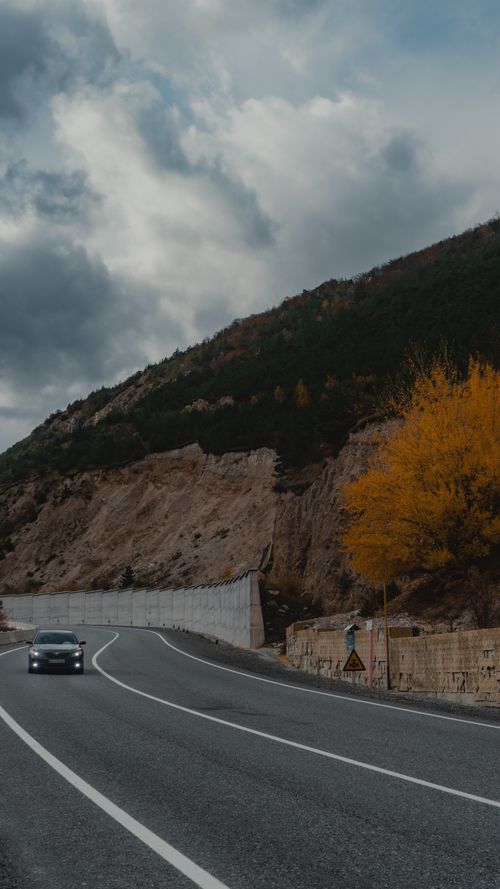 Free Captivating mountain road in North Ossetia, Russia during autumn with vibrant foliage and overcast sky. Stock Photo