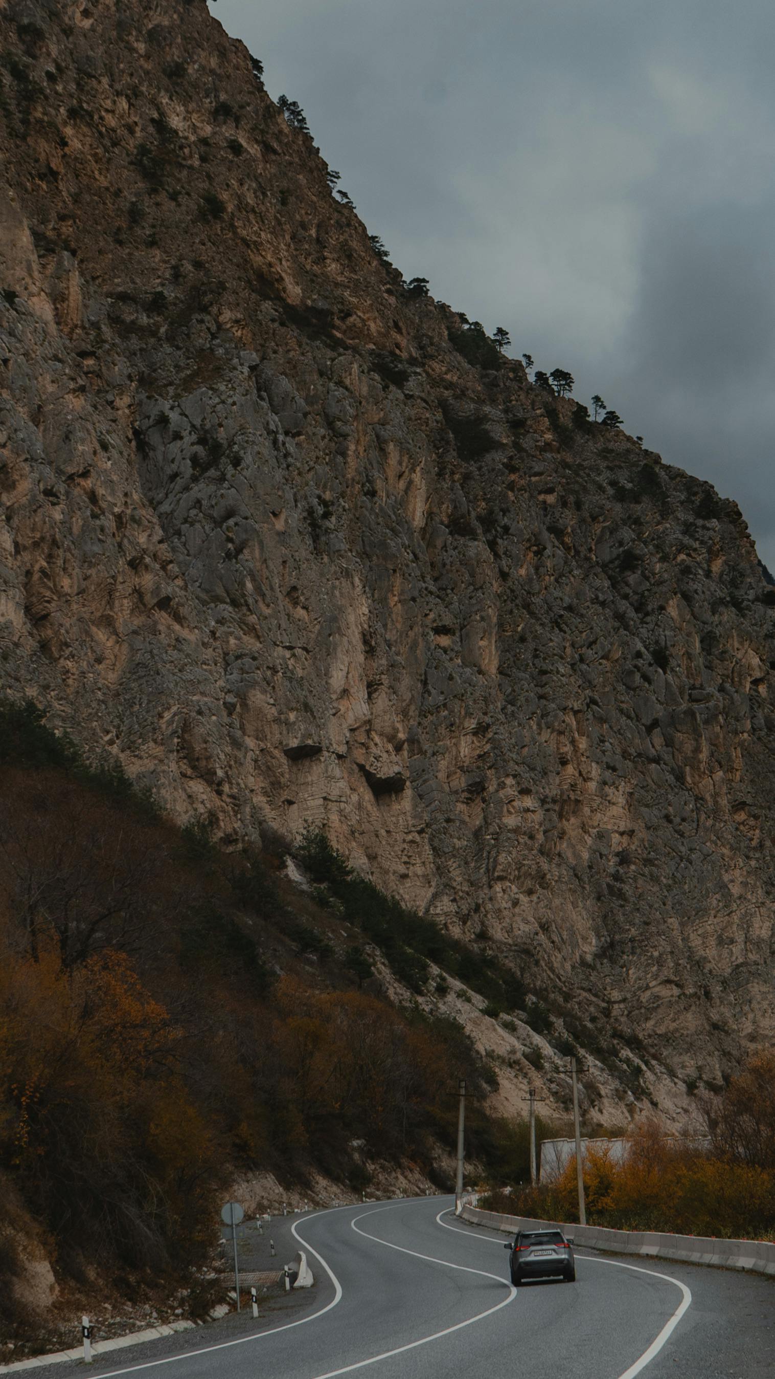 Gratuit Drum șerpuitor prin munții accidentați din Osetia de Nord-Alania, Rusia, sub cerul înnorat. Fotografie de stoc