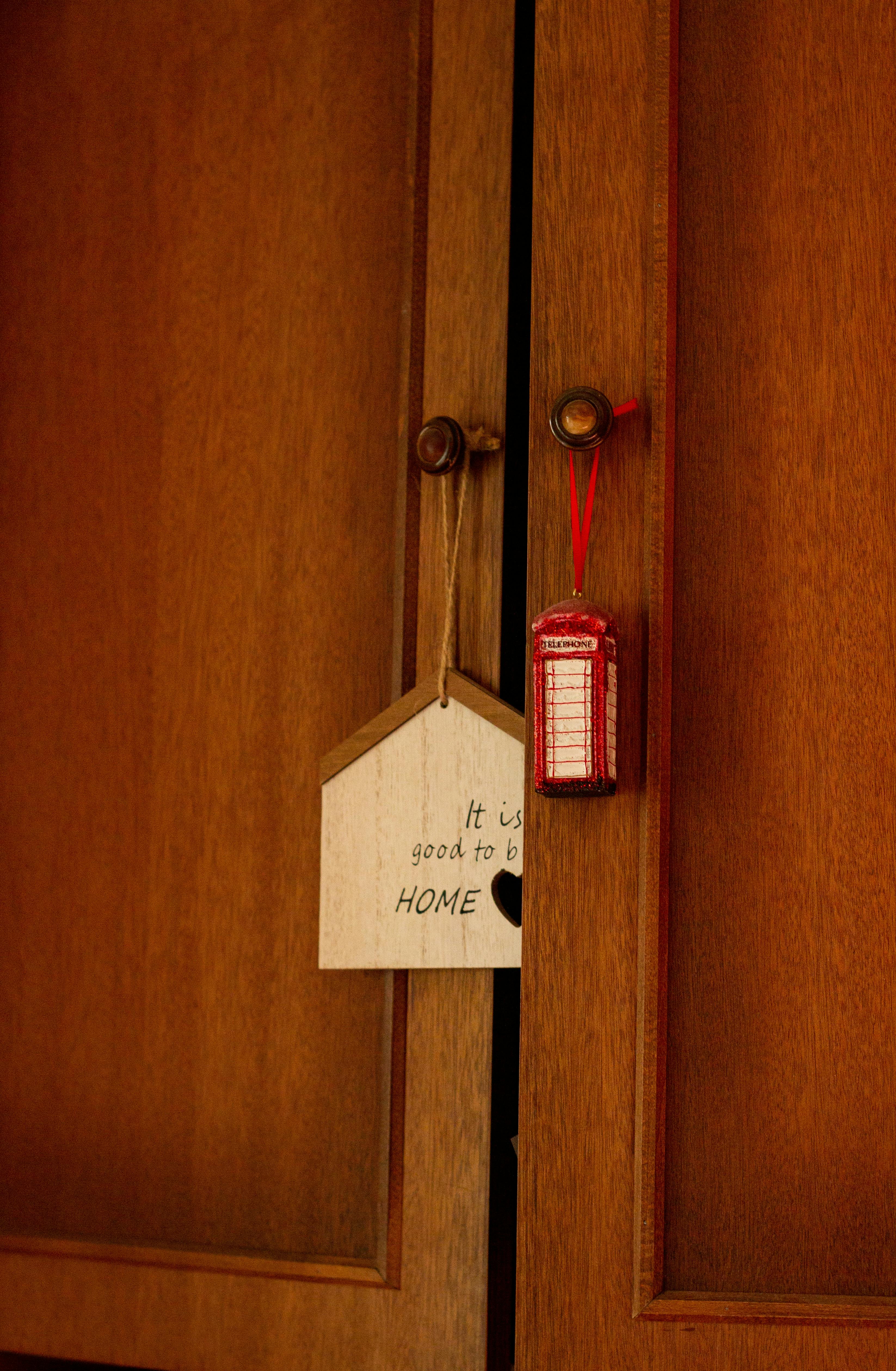 Gratuit Un dulap din lemn cu o etichetă decorativă „Good to be Home” și o mini-cabină telefonică roșie. Fotografie de stoc