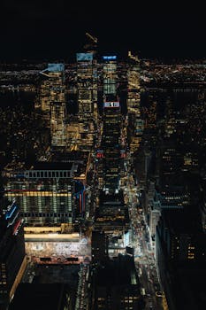 Stunning aerial view of New York City skyline shining bright at night showcasing skyscrapers and bustling streets.