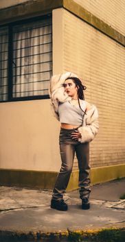 Stylish woman in fur coat poses confidently in urban environment.