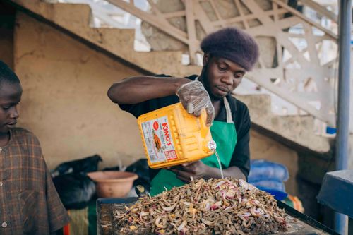 Free Street vendor pouring cooking oil on food outdoors. Traditional cooking setting. Stock Photo