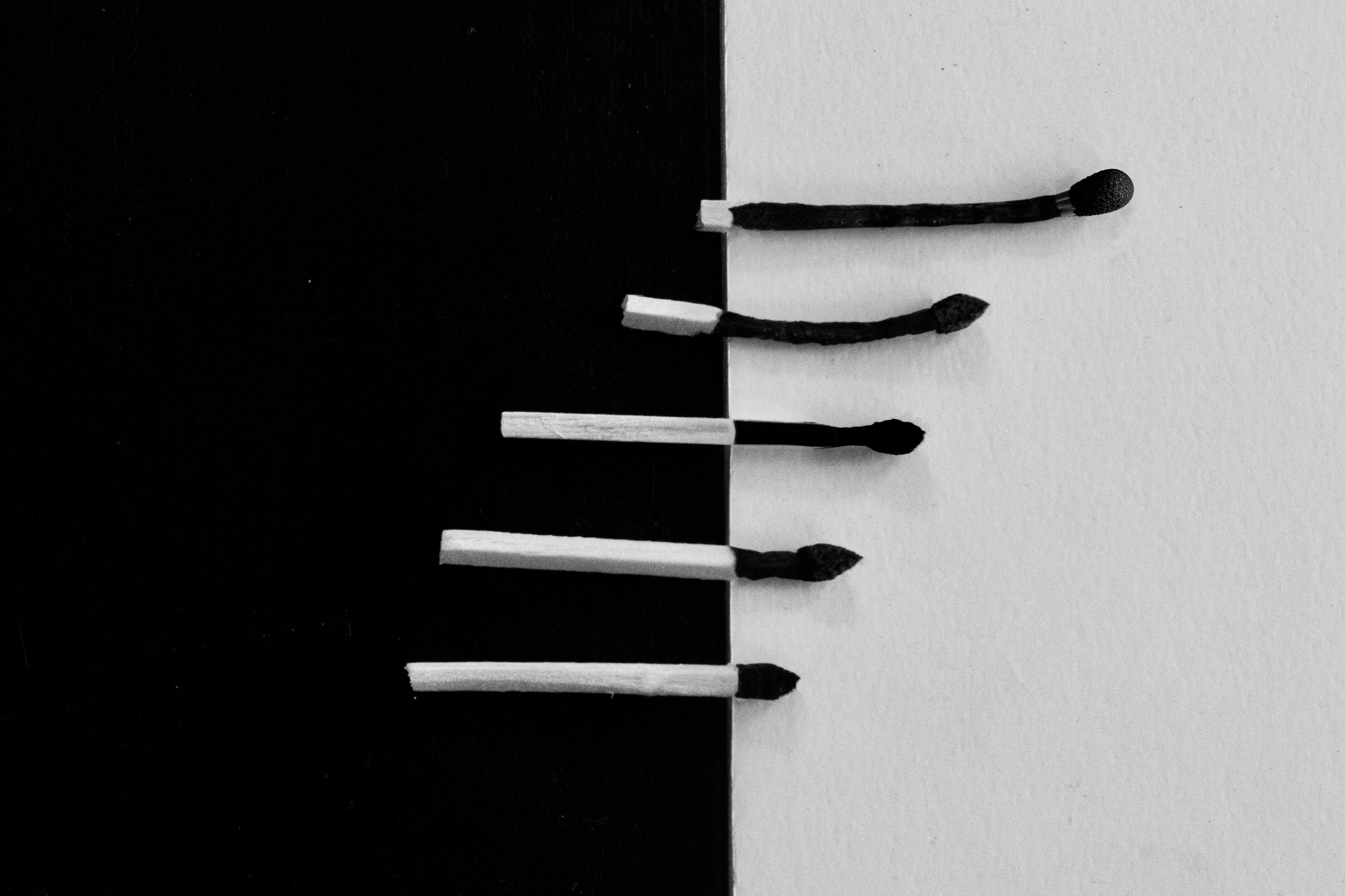 Free A conceptual black and white image of burnt matches aligned on a divided background, symbolizing contrast. Stock Photo