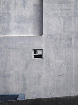 A small window on a large, concrete wall showcasing minimalist architecture in Chennai, India.