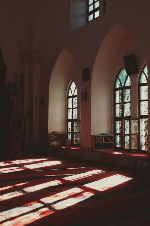 Free Sunlight streaming through arched stained glass windows in a historic mosque interior in Bursa, Türkiye. Stock Photo