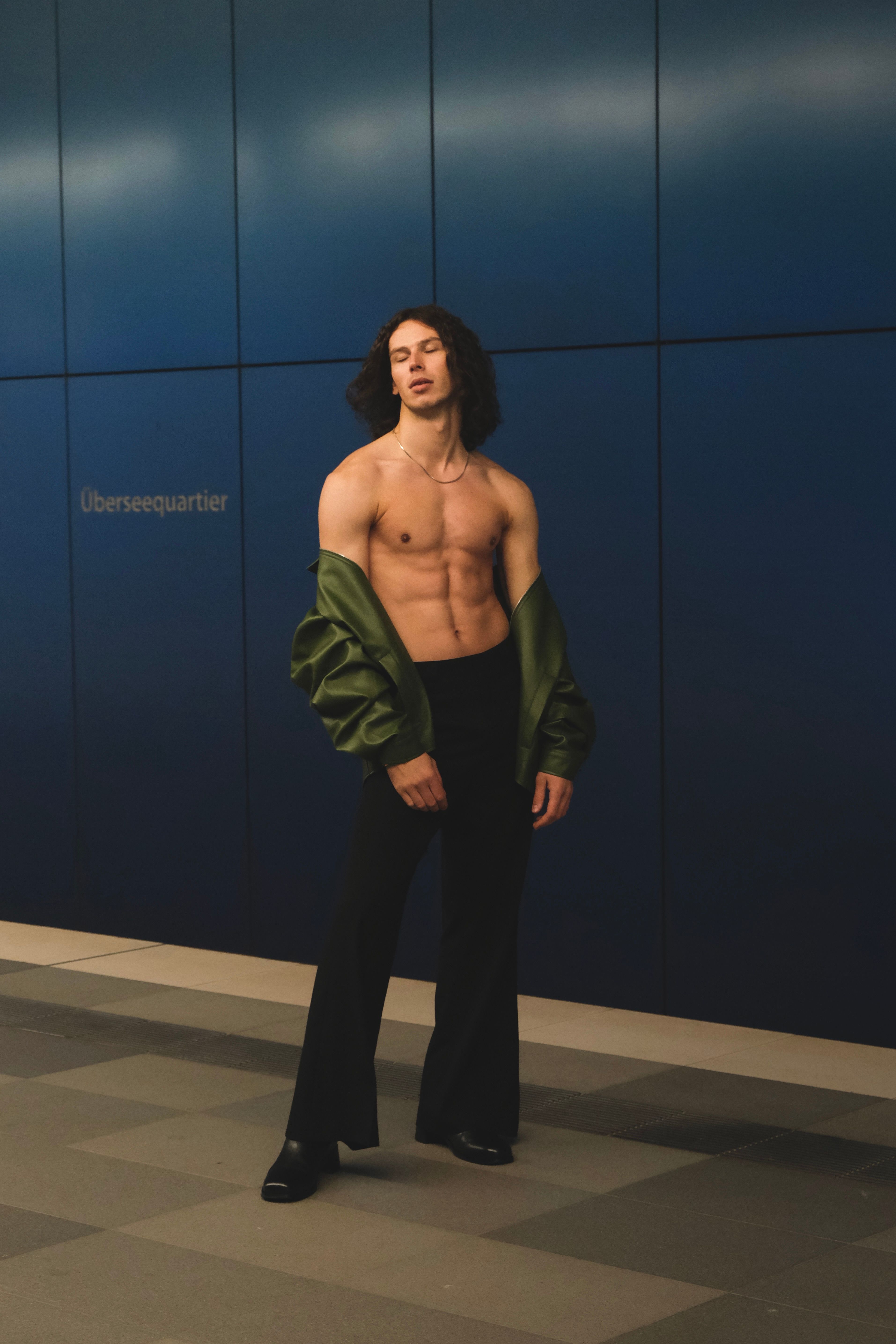 Shirtless male model posing in urban environment with sleek style.
