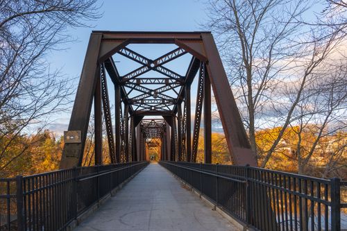Free Beautiful fall scene of a historic railroad bridge in Auburn, Maine with vibrant autumn foliage. Stock Photo
