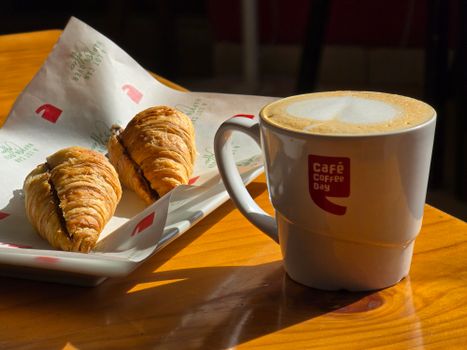 Cup of coffee and croissants at a café table, perfect breakfast scene.