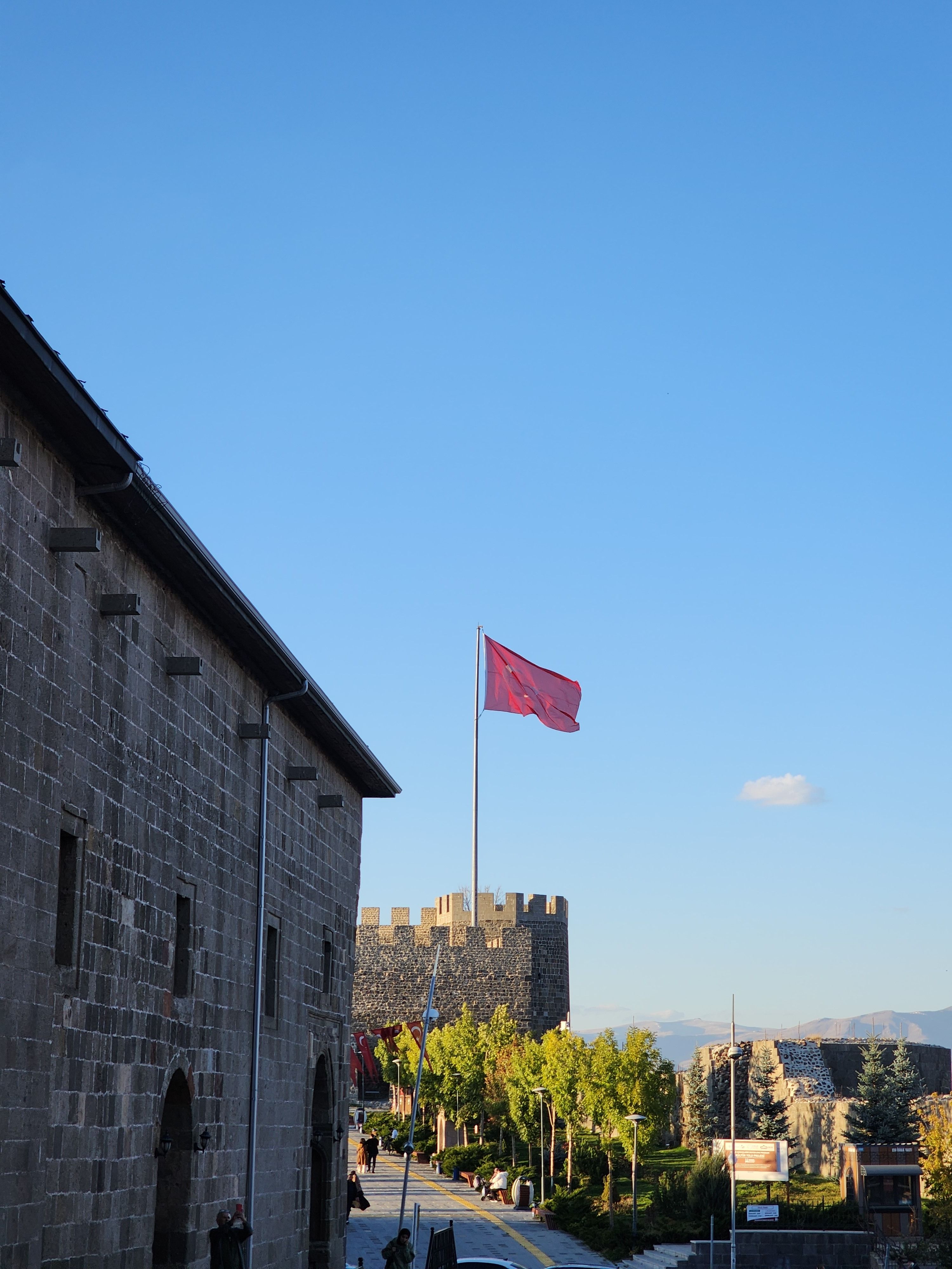 Stone fortress in Erzurum with the Turkish flag against a clear sky.