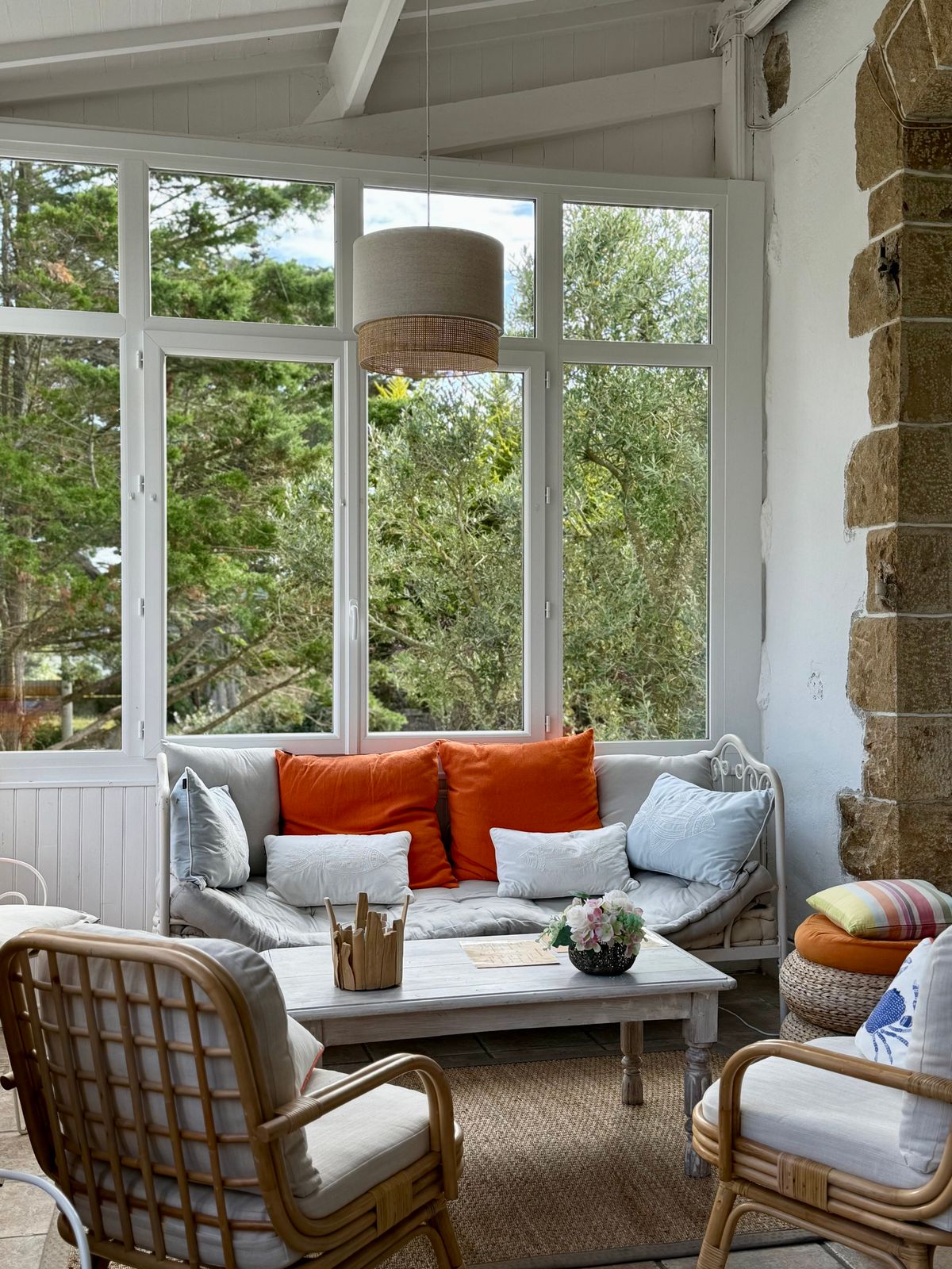 Wohnwintergarten mit Rattanmöbeln, hellen Kissen und großen Fensterflächen