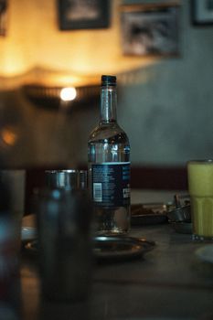 Dimly lit scene of a restaurant table with various bottles and glasses, creating a cozy atmosphere.