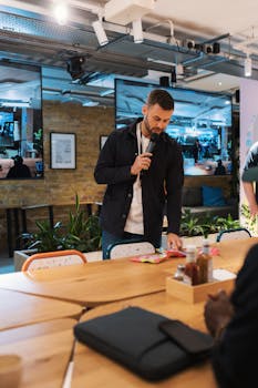 Professional speaker presenting in a stylish, modern office environment with screens and plants.