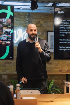 A man conducting a presentation with slideshow screens in an indoor setting.