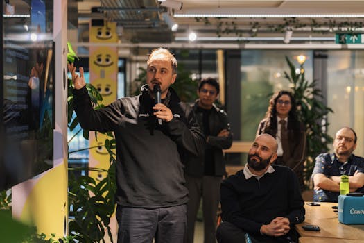 A presenter delivers a business presentation in a modern office environment with attentive audience members.