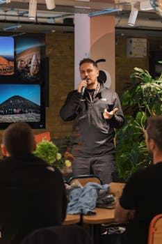 A man presenting to a seated audience with visuals on screen.