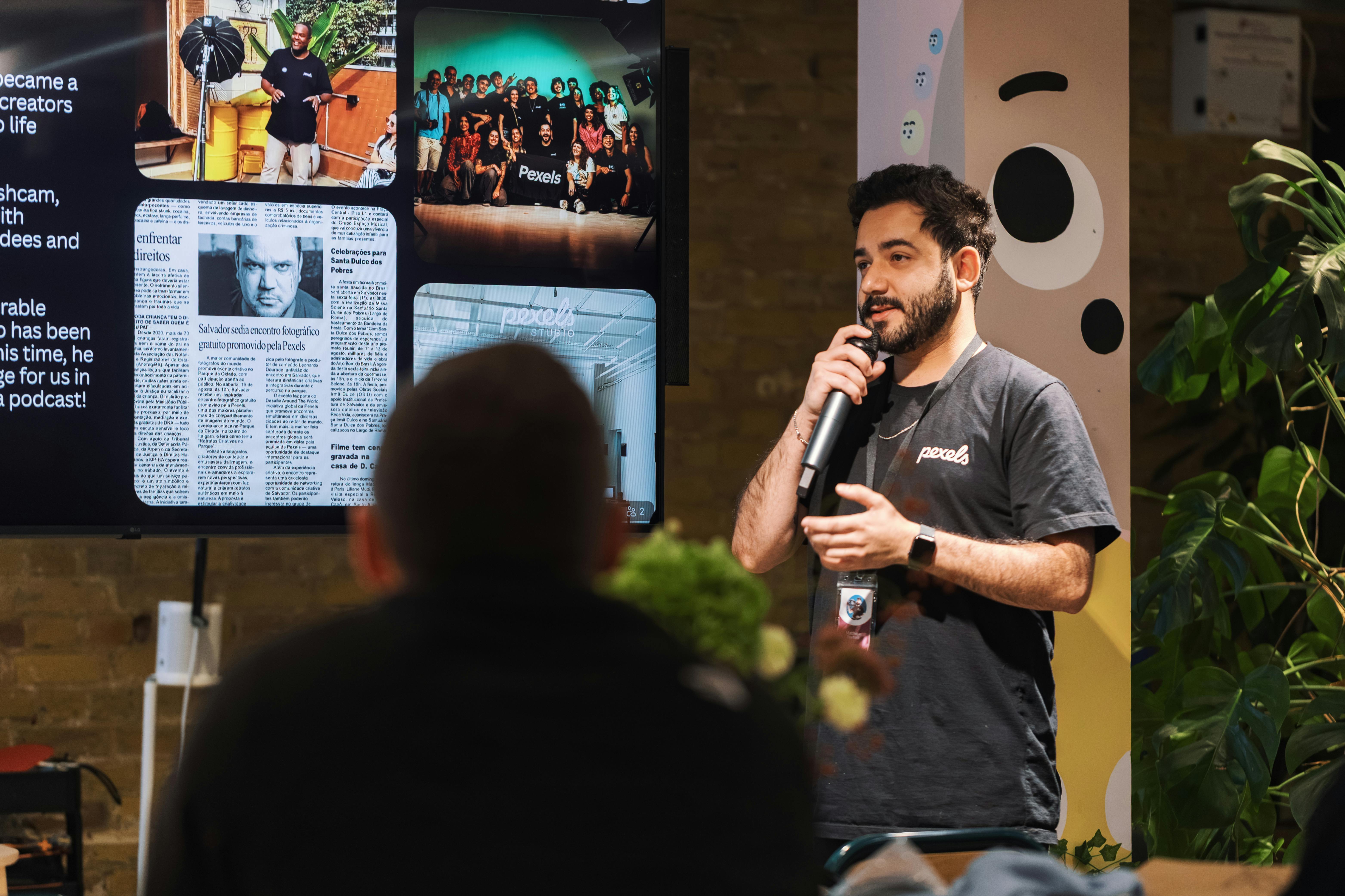 MC speaking with a microphone in front of a presentation screen