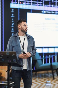 Man presenting at a business conference with digital display