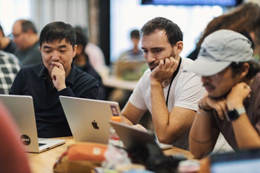 A diverse group of professionals working together on laptops in a modern office environment.