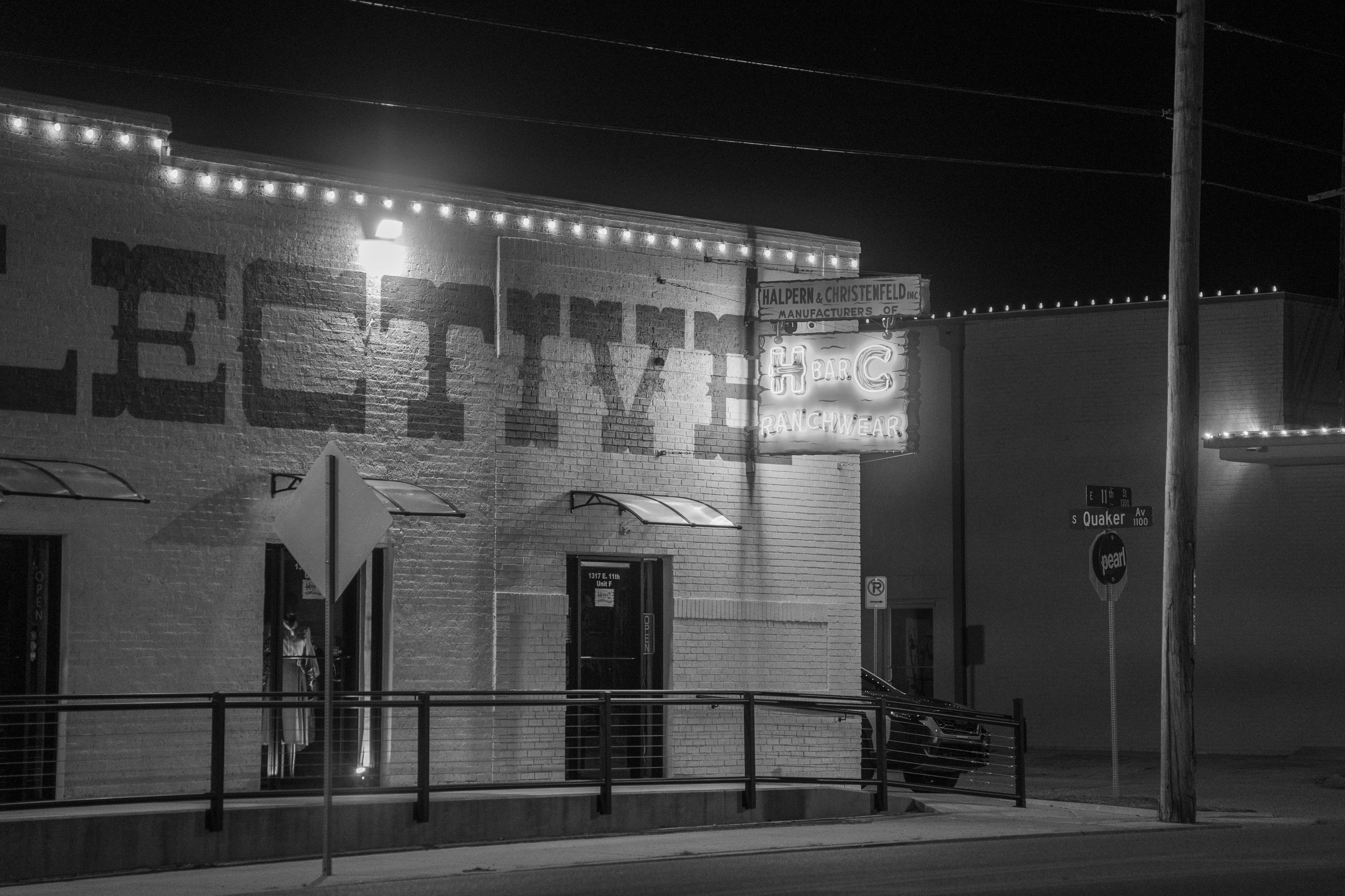 Безкоштовне Чорно-біле фото вітрини магазину з неоновими вивісками та вуличним освітленням, зняте вночі. стокове фото