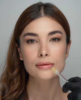 Woman receiving a cosmetic lip injection by a professional in a clinical setting.