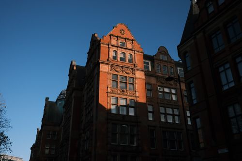 Free A historic brick building in the city highlighted against a clear blue sky. Stock Photo