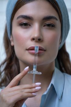 Close-up of a woman holding a syringe, conveying beauty and healthcare themes.